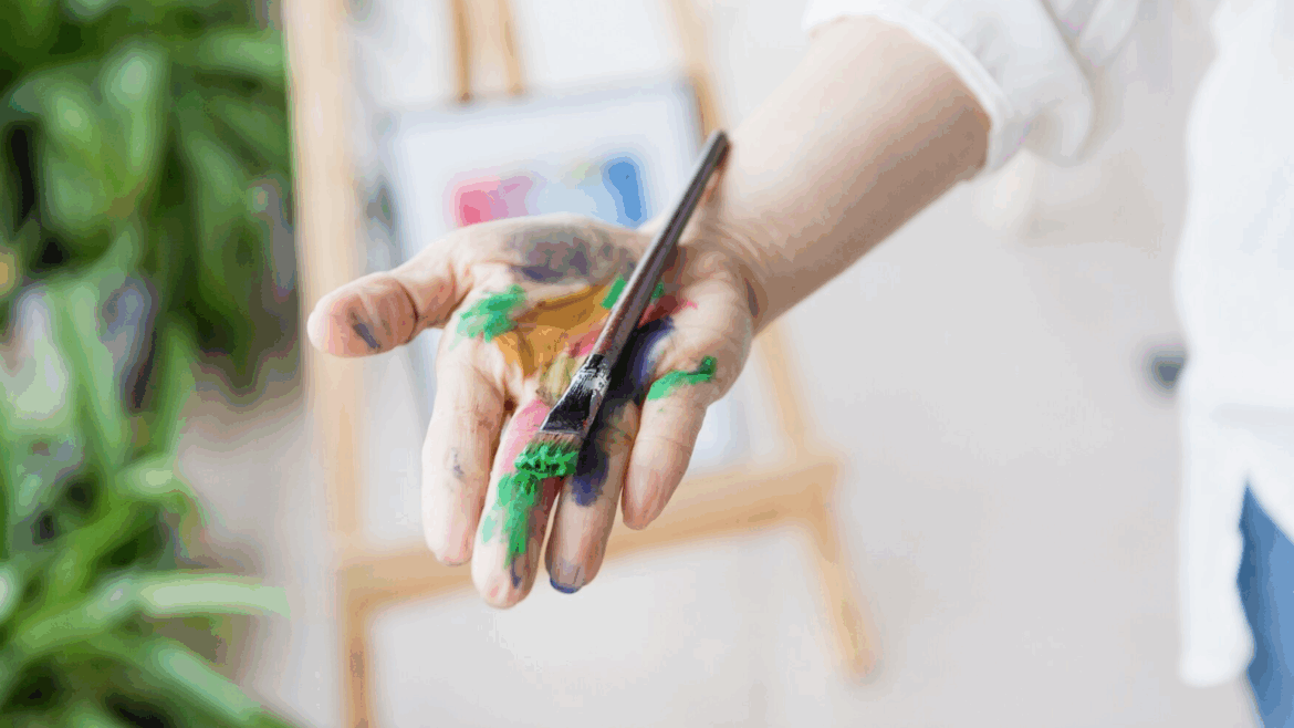 Image d'une main et d'un pinceau avec des tâches de peinture